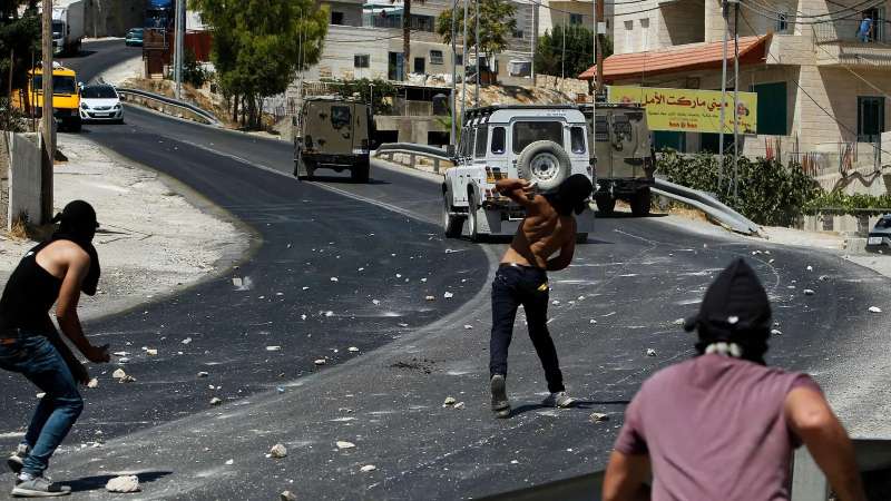 متظاهرون فلسطينيون يرمون جنود إسرائيليين بالحجارة بالضفة